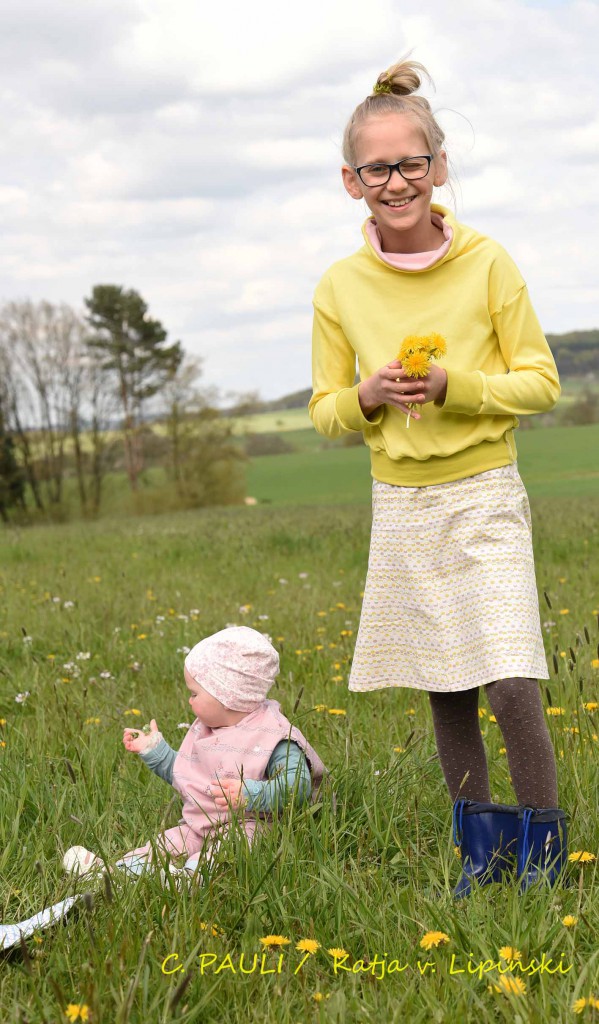 Na ja, da haben wir halt Blumen gepflückt. Mia pflückt ein Sträußchen passend zu ihrem Outfit: Sonnemgelber Löwenzahn zum sonnengelben Interlock.